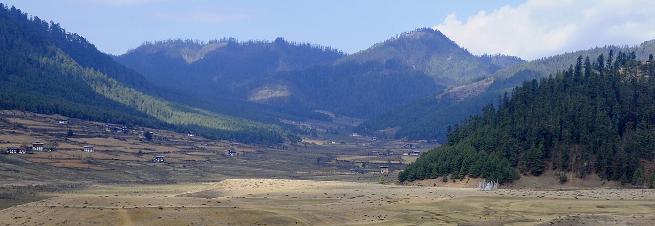 The open landscape of Phobjikha Valley beneath Bhutan’s forested mountains